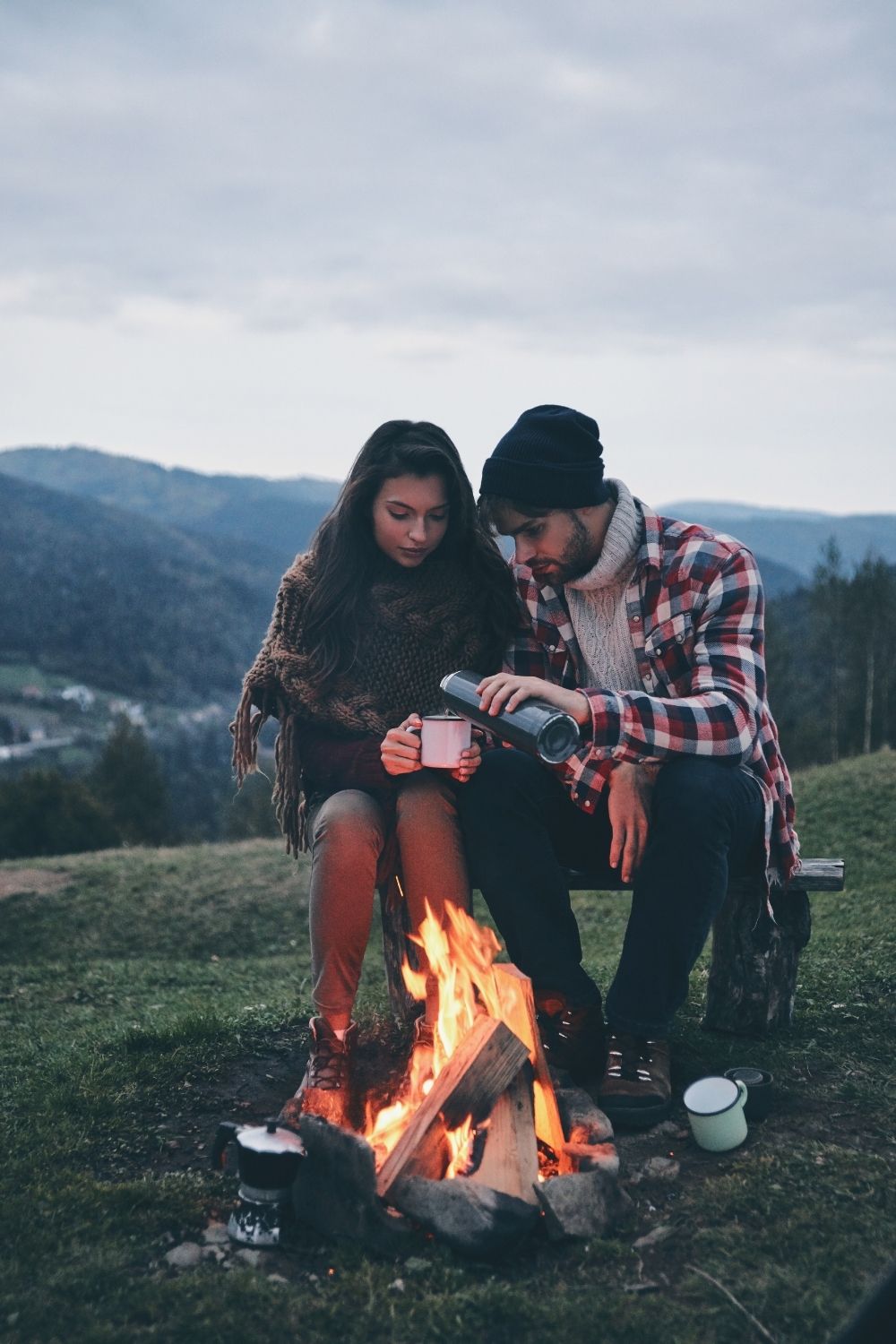 A couple sitting by a fire.